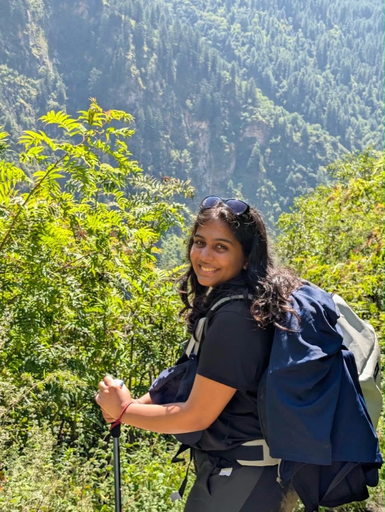 Saathvika on a mountain trail with a pack and trekking pole